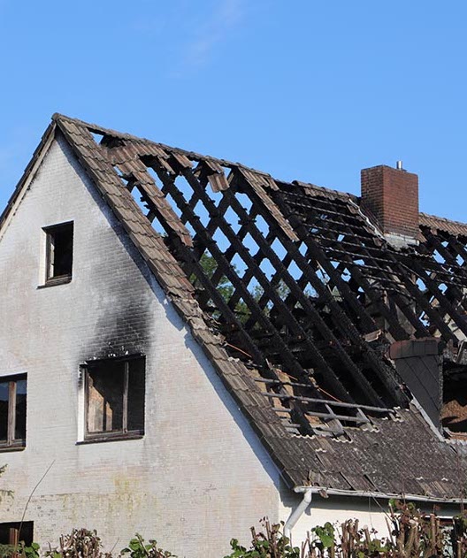 House with roof that has been badly damaged by fire